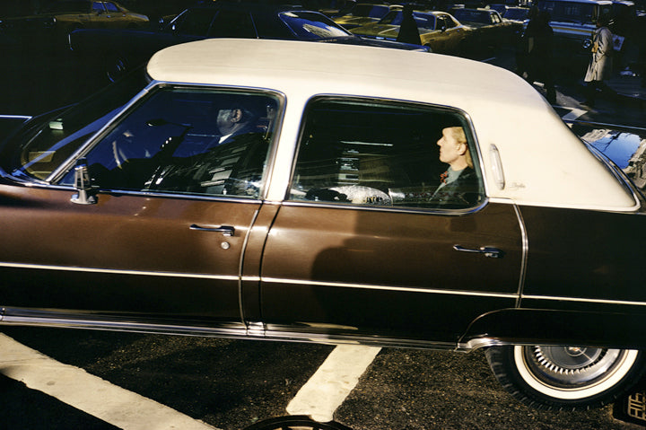 Woman in back of classic brown car with white roof in NYC
