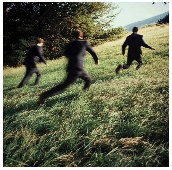 Three men in black suits running on a green hill