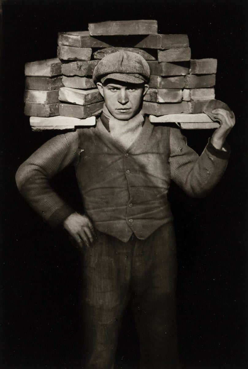 black and white portrait of bricklayer holding bricks on his shoulder