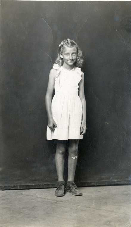 black and white photo of a young child in front of a dark wall