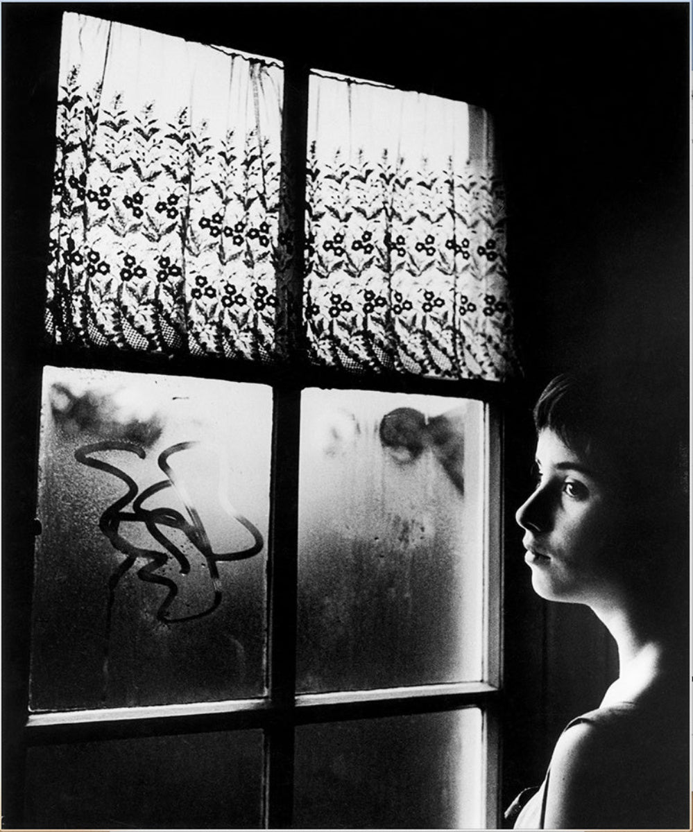 black and white portrait of girl behind window