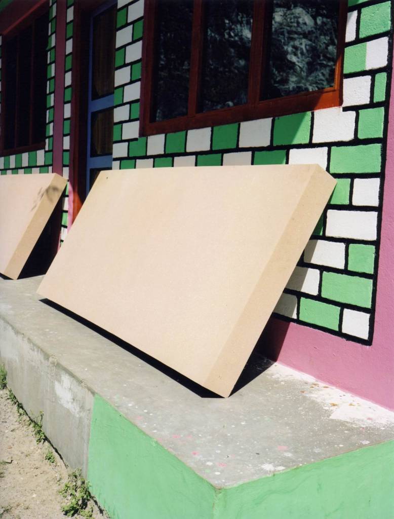 vertical photo of a mattress leaning against a colourfull wall