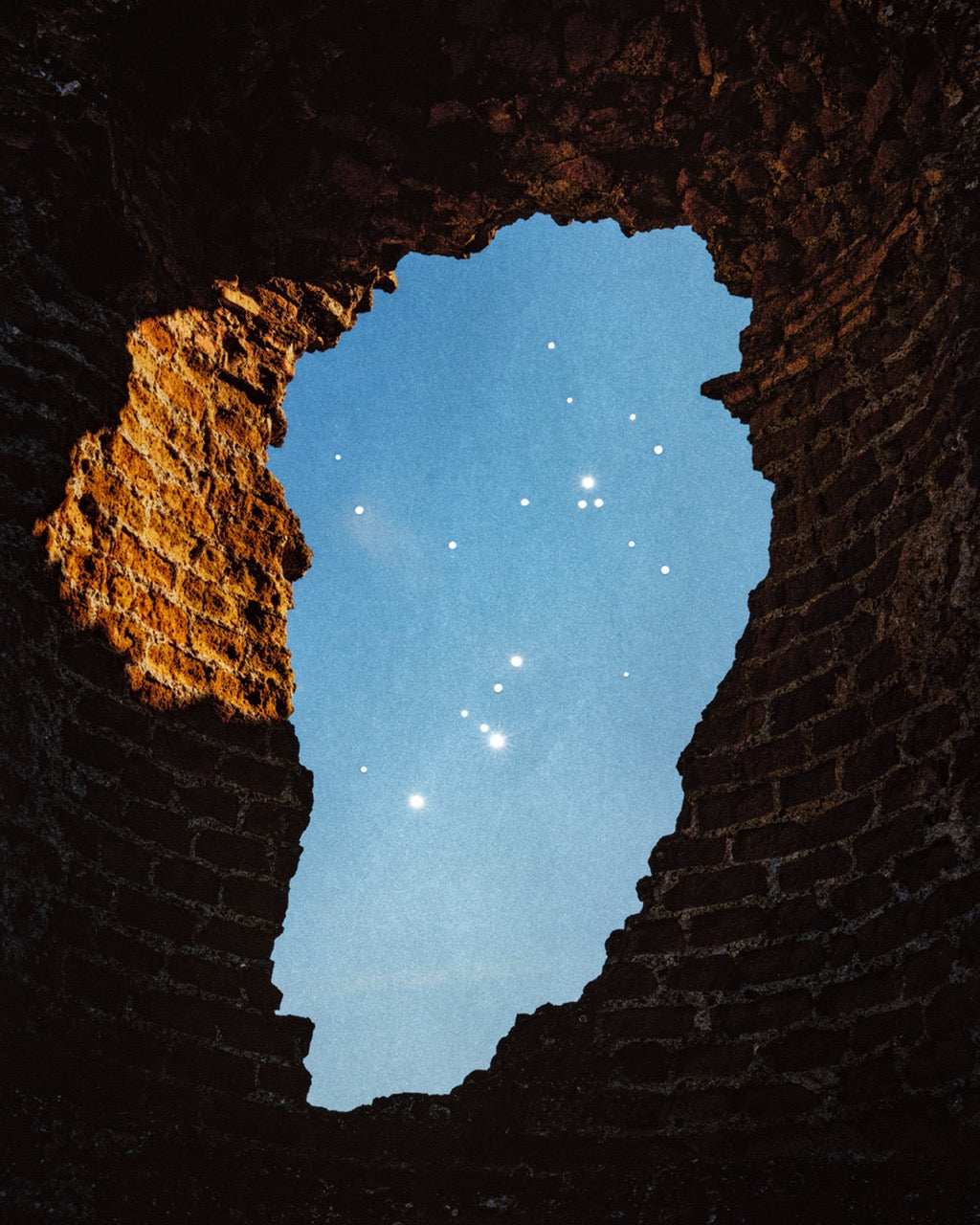 Brick towerlike construction with an oval shaped opening from which we see a blue starry sky.