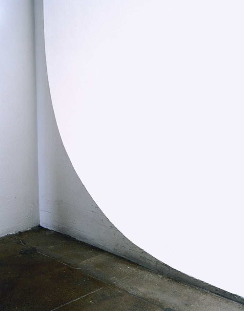 Corner in white wall with grey floor tiles.