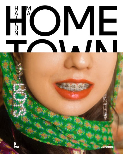 Bookover of Hailun Ma's Homeland book, with on the bottom half a horizontal image of a woman with braces, a shiny Boys earring and red lipstick. The top half of the book shows the name and title in black letters on a white background. 