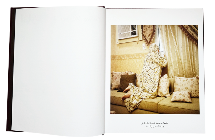 spread book with on the right page a photo in yellow tones, with a woman sitting on the sofa watching outside