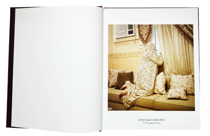 spread book with on the right page a photo in yellow tones, with a woman sitting on the sofa watching outside