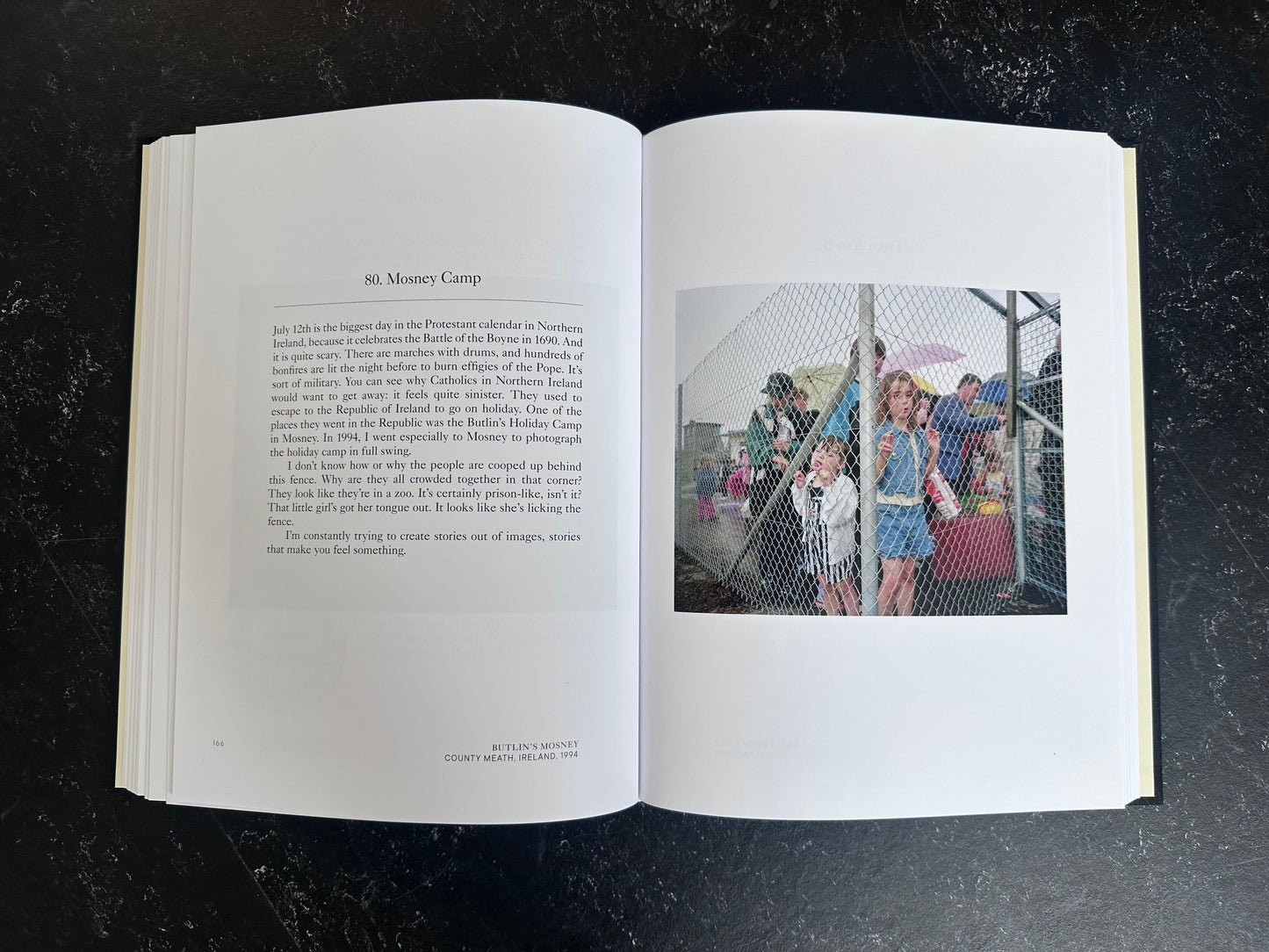 Spread with text on the left page and one colour photo on the right of people behind a wired fench.