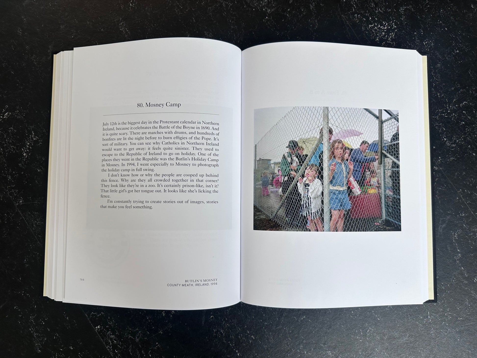 Spread with text on the left page and one colour photo on the right of people behind a wired fench.
