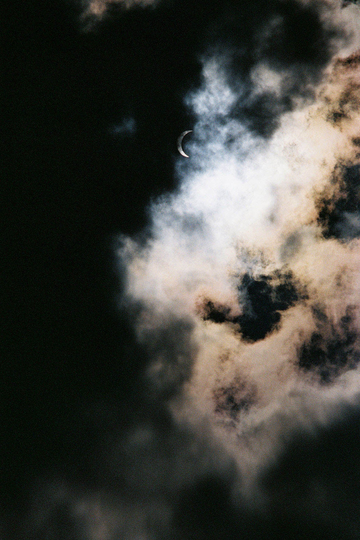 Colour photo of a sky at night with the moon and clouds.