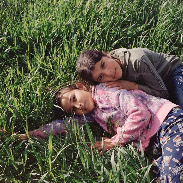 Two girls laying in a green field, almost on top of each other