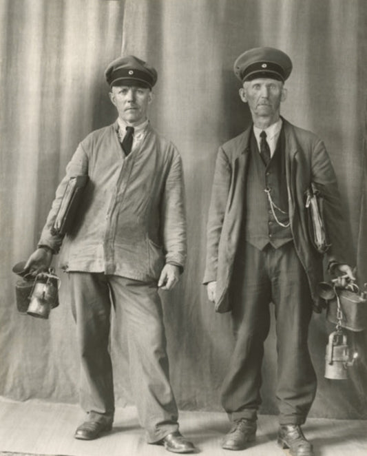 black and white portrait of two gasmen in front of curtain in studio