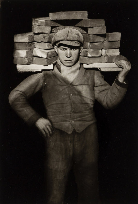 black and white portrait of bricklayer holding bricks on his shoulder