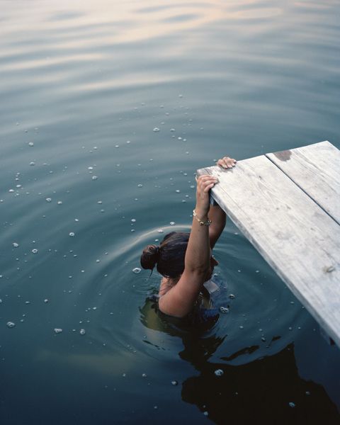 woman in water holding on to a diving board