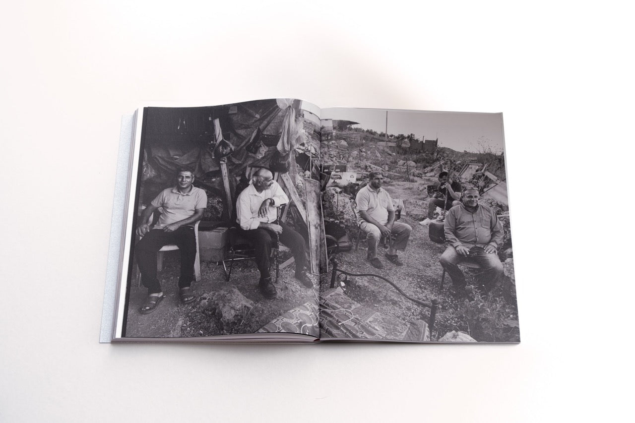 spread foam magazine the test of time showing a black and white image by sakir khader showing a group of mean sitting outside in debres