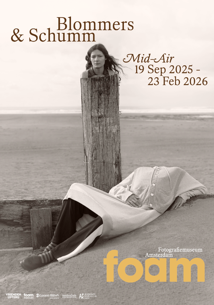 black and white image of a woman's head on a pole on the beach, with a headless body laying on the sand, next to the pole