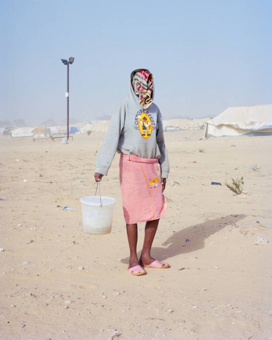 figure wearing a blue hoodie and pink skirt carrying a white bucket 