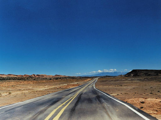 landscape image of a road mountains and a blue sky