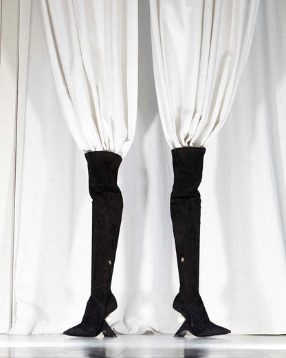 two high black boots standing up with white curtains in them, blending in the background